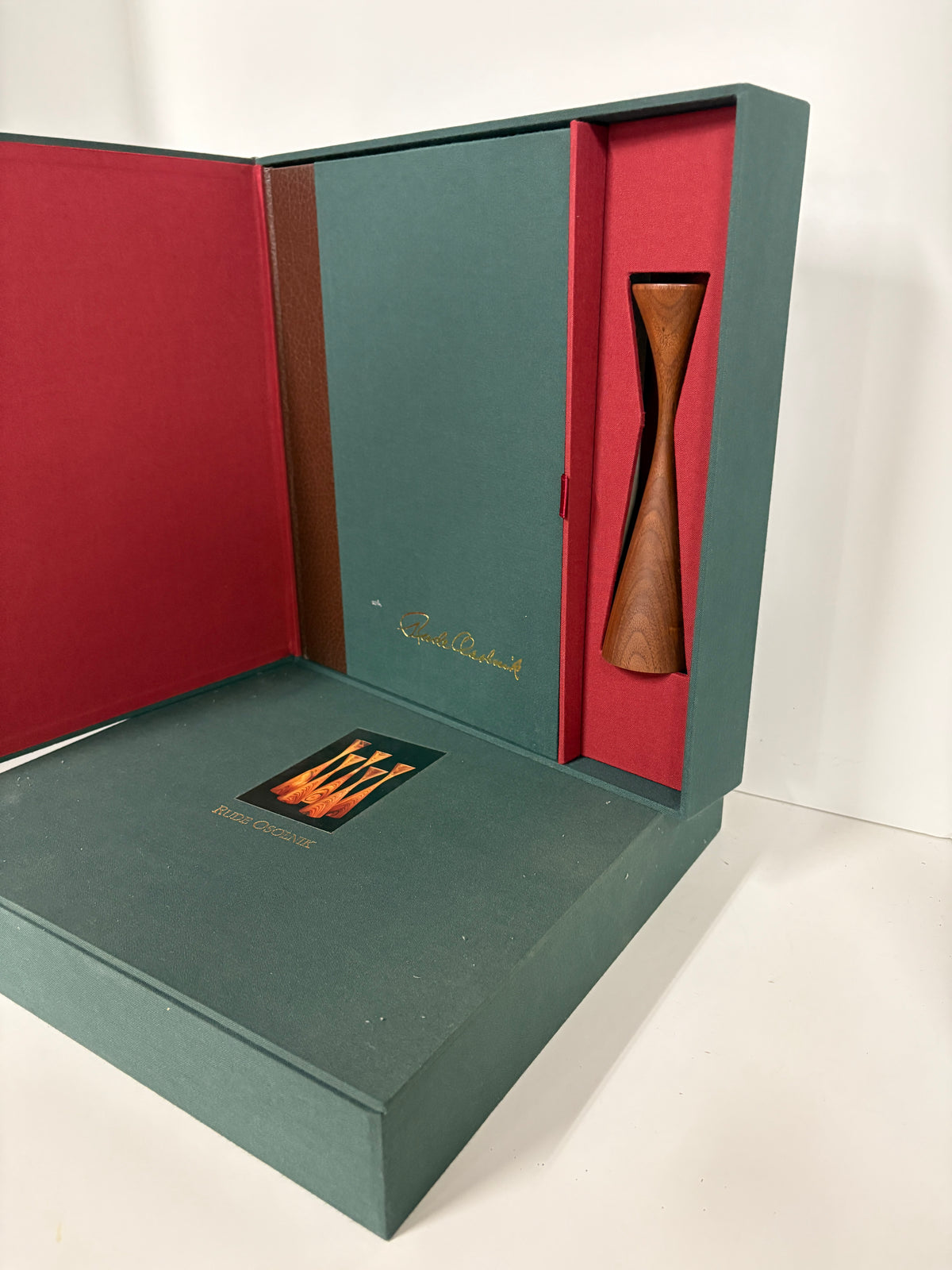 Rude Osolnik special edition slipcase open displaying signed monograph and turned walnut candleholder with red velvet interior"