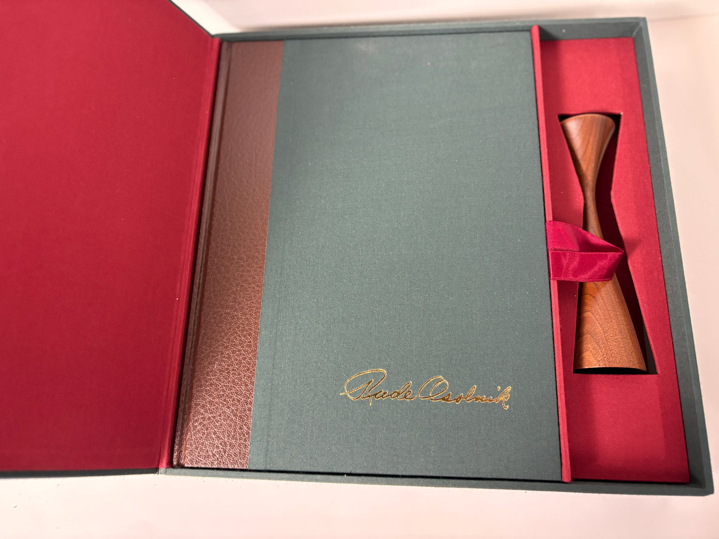 Green leather-bound book with gold embossed text and a One of his candleholders.

