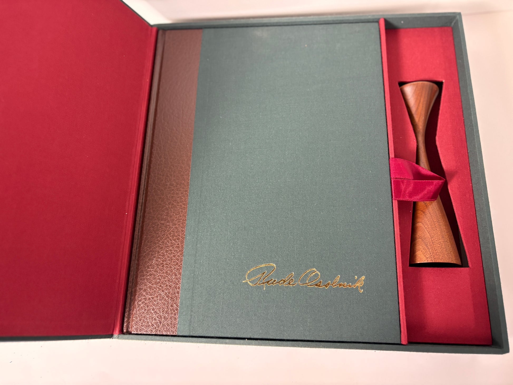 Green leather-bound book with gold embossed text and a One of his candleholders.

